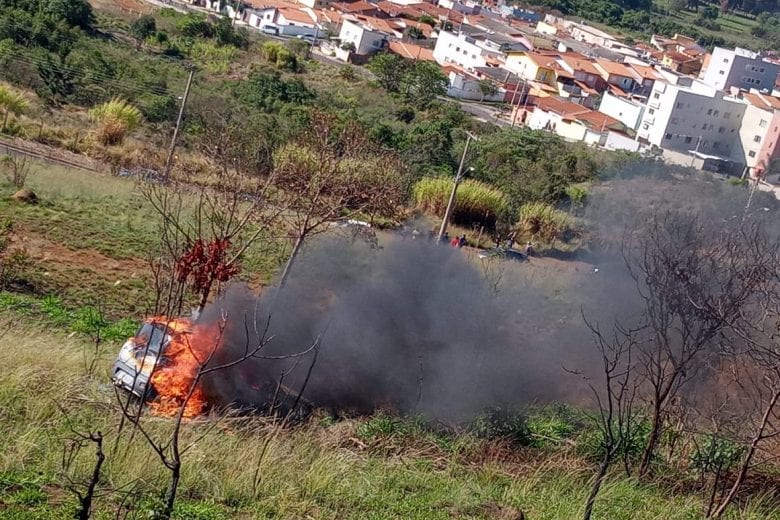 Carro pega fogo após cair em ribanceira e mulher é socorrida