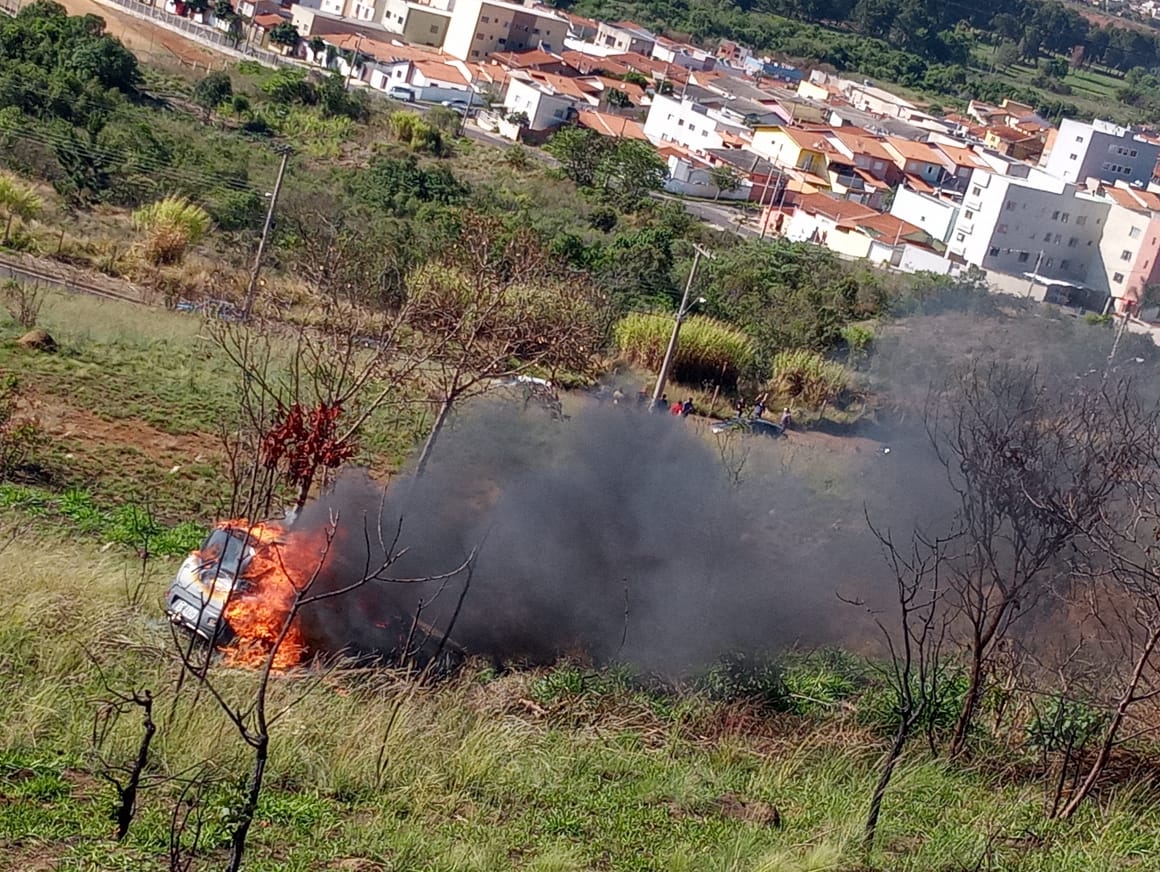 Carro pega fogo após cair em ribanceira e mulher é socorrida